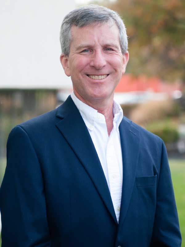 A photo of Dan Littman wearing a navy suit with a white dress shirt.