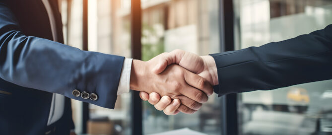 Business professionals shaking hands over a signed contract, symbolizing successful financial and accounting partnerships at LedgerLogix.