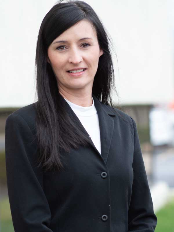 A photo of Elizabeth Koehler wearing a black blazer over a white top.