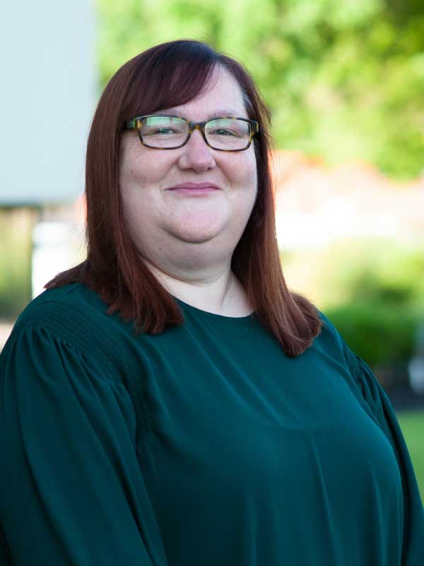 A photo of Elizabeth Walsh wearing a forest green blouse.